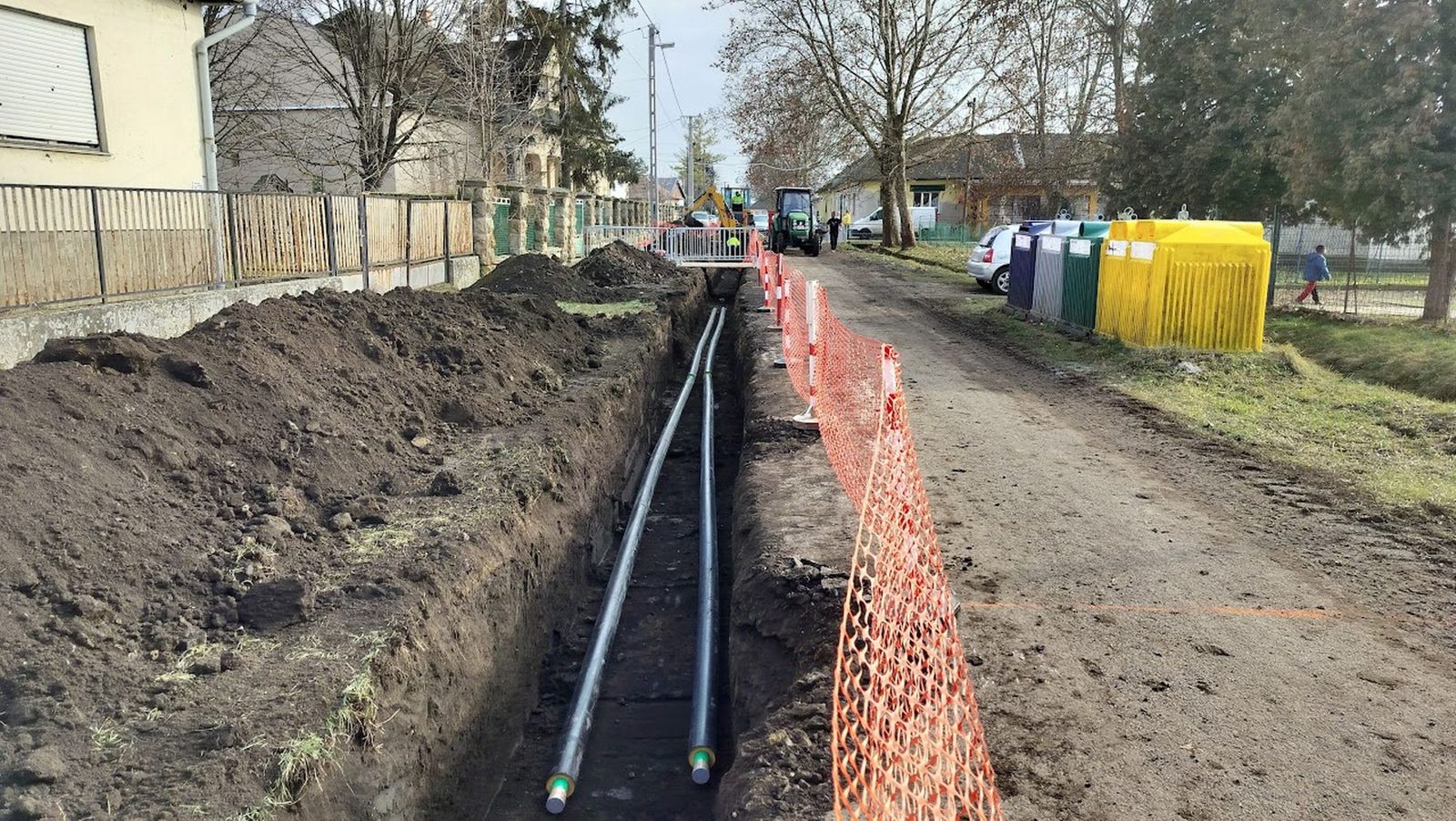 Kiásott árokban lefektetett előszigetelt távhőcsövek a falu utcáján